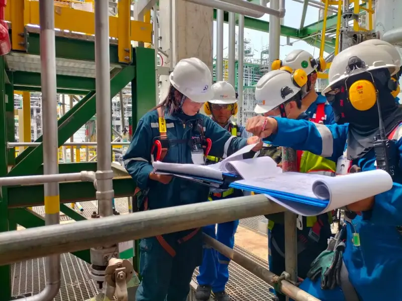 Site team in full protective equipment reviewing drawings on a platform